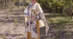 Ruana abierta color crema con estampado de hojas color naranja.