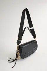 Cartera bandolera de tamaño compacto en color negro, con diseño estructurado y solapa frontal. Cuenta con doble opción de transporte: una asa corta fija y una correa larga estilo deportivo, regulable y extraíble. Incluye un llavero decorativo con dije de raqueta y cordones, y cierre principal con cremallera y broche imantado.