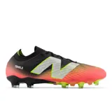 Championes de fútbol New Balance Tekela V4 Pro FG, color negro con degradado a naranja y detalles en verde neón. Presentan el logo de la marca en plateado y suela con tapones verdes.