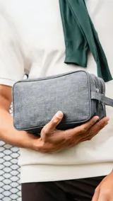 Neceser gris de tela canvas con doble cierre superior, compartimentos individuales, bolsillo frontal con cierre y correa de mano.