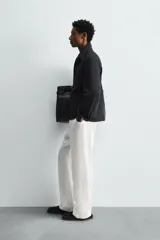 Camisa polo de denim negro con mezcla de algodón y cáñamo. Cuello polo con cierre frontal de tres botones. Manga larga con puño abotonado. Bolsillos de plastrón en el pecho y en la cadera.