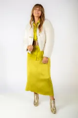 Tapado corto de piel sintética en color crudo, con diseño de manga larga y cierre frontal mediante broche metálico dorado.