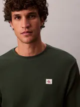 Remera de manga larga Calvin Klein en color verde oscuro, confeccionada en tejido térmico de punto con textura de nido de abeja. Cuenta con cuello redondo, puños acanalados y un pequeño parche con el logo de la marca en el pecho.