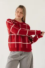 Sweater de punto color rojo con diseño de cuadrícula en color blanco, de corte holgado, cuello redondo y mangas largas con puños acanalados.