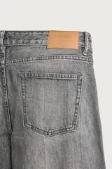 Jeans regular fit de mezclilla negra con efecto lavado, corte recto y tiro medio. Cuenta con diseño de cinco bolsillos y cierre frontal con cremallera y botón.