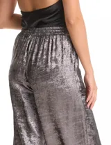 Pantalón de corte wide leg en tejido laminado metalizado color gris. Presenta pretina ancha elastizada con lazo de ajuste y bolsillos delanteros.