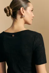 Top de manga corta confeccionado en tejido jacquard con textura en relieve. Presenta escote en V y un diseño frontal con líneas diagonales que crean un efecto cruzado.