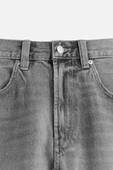 Bermuda de denim de algodón, color negro lavado, de corte ancho (baggy fit) y tiro medio. Presenta cinco bolsillos y bajo con acabado irregular deshilachado.