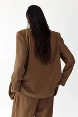 Blazer color marrón levemente largo con solapas de muesca, hombreras y doble botonadura frontal. Cuenta con bolsillos delanteros ribeteados con solapa y diseño forrado.