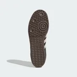 Zapatillas Adidas Samba OG con exterior de cuero azul marino y detalles en gamuza beige. Presentan las icónicas tres tiras laterales, suela de goma color marrón y el nombre del modelo en letras doradas.