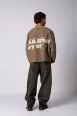 Buzo oversize de corte boxy, confeccionado en algodón rústico de alto gramaje en color beige. Presenta cuello redondo con borde crudo, mangas largas y una estampa frontal con el texto VCP delimitado por líneas horizontales blancas.