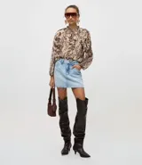 Blusa de chiffon con estampado paisley en tonos marrones y beige, de corte holgado y manga larga con puños ajustados. Presenta cuello alto con lazo frontal y detalles de volados en el frente.