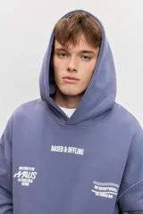 Canguro de friza color azul acero, con capucha, bolsillo tipo canguro y estampado gráfico en el pecho con texto en blanco.