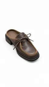 Zueco de cuero marrón con punta cuadrada, detalles de gamuza en los bordes y cordones de cuero ajustables en la parte superior.