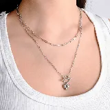 Collar doble de cadena plateada con eslabones rectangulares y dije de corazón con cierre tipo barra en T.