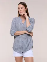 Blusa de silueta relajada con textura tramada, color azul con rayas verticales en tonos rosados, celestes y amarillos. Cuenta con cuello mao abierto en V y mangas tres cuartos amplias con pequeña abertura lateral en el puño.