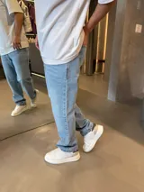 Jean de corte baggy en color azul claro, con diseño de cinco bolsillos y cierre frontal con botón y cremallera.
