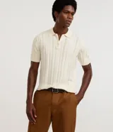 Camisa polo texturizada de manga corta, color blanco, con cuello polo y cierre frontal de cremallera corta, de diseño regular.