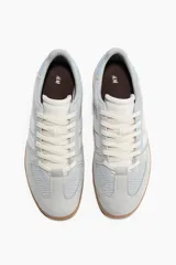 Championes de diseño urbano, en tonos celeste y gris, con detalles en blanco y suela de goma marrón.