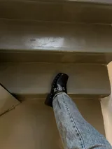 Zuecos negros de cuero encerado con detalle de tachas plateadas en la base y hebilla metálica en el empeine.