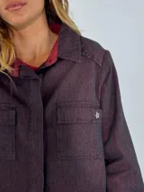 Chaqueta tipo camisa de denim color borgoña, con cuello clásico, manga larga, cierre frontal con botones y bolsillo de parche en el pecho.