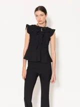 Top negro de lycra doble bifaz con mangas japonesas y escote en la espalda. Presenta detalles fruncidos en el delantero y cintura con volado caracol. Se accede mediante tiras en la espalda superior y un cierre desmontable.