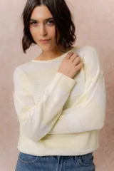 Buzo de tejido liviano con diseño de rayas horizontales en tonos amarillo manteca y blanco, cuello redondo y mangas largas con puños tejidos.