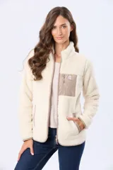 Campera de sherpa color beige con cuello alto y cierre frontal. Presenta un bolsillo frontal en el pecho de gamuza color arena con cierre y etiqueta decorativa, además de detalles en gamuza en los bordes.