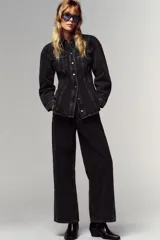 Camisa de denim color negro gastado, corte entallado, cuello solapa, manga larga, bolsillos delanteros con solapa y cierre frontal con botones dorados.