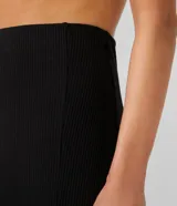 Falda midi negra de rib, con abertura lateral.