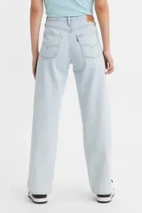 Pantalón jean celeste de corte ancho, con tiro medio, cierre con botones y aberturas en el ruedo.