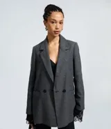Blazer alargado de Blue Steel confeccionado en tejido polivelour con textura, de corte recto y estilo sastrero. Presenta cuello con solapas clásicas, cierre frontal con dos botones y bolsillos laterales. El diseño incluye detalles de encaje en los puños.