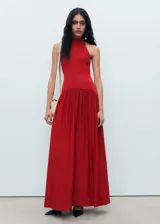Vestido largo rojo de punto combinado, con cuello halter, sin mangas y diseño evasé con falda fluida y amplia.