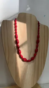 Collar de diseño artesanal compuesto por una combinación de cuentas cilíndricas estriadas y esferas lisas en color rojo intenso.