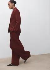 Chaqueta de traje color bordó con solapas de muesca, cierre frontal de un botón, bolsillos con solapa y forro interior.