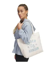 Bolso tipo tote de lona color crema con estampado gráfico de la marca Under Armour en color azul claro. Cuenta con un amplio compartimento principal y correas para llevar al hombro.