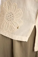 Remera marrón de algodón peinado flame, con escote en V, mangas cortas y diseño bordado de flores en tono sobre tono.