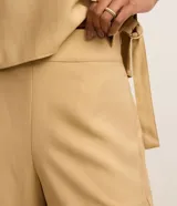 Bermuda Marfinno de talle alto y corte recto, confeccionada en viscosa twill color beige. Cuenta con cierre lateral mediante cremallera y detalle de ruedo italiano o plegado hacia afuera.