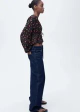 Blusa crop de viscosa con estampado floral, cuello en pico, manga larga con puños elásticos y detalle de lazo ajustable en la cintura con fruncido.