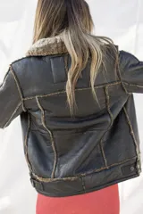 Campera tipo gamulán de cuero genuino color negro, con interior y cuello de piel sintética en tono grisáceo. Presenta cierre frontal, costuras visibles y diseño estructurado.