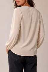 Blusa celeste de manga larga con escote en V y volados en cascada ribeteados en color oscuro. Cuenta con puños elásticos.