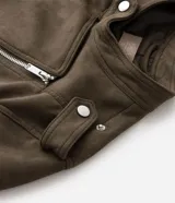 Campera estilo biker confeccionada en gamuza sintética color verde militar. Presenta cierre frontal asimétrico con cremallera metálica, cuello con solapas y botones a presión, y bolsillos laterales con cierre. Incluye detalles de charreteras en los hombros.