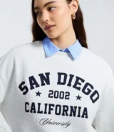 Buzo gris melange de cuello redondo con estampa frontal estilo universitario "SAN DIEGO 2002 CALIFORNIA", confeccionado en algodón con felpa y detalles acanalados en puños y ruedo.