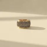Anillo de banda ancha con bordes en oro y centro de plata pavimentado con circonias brillantes.