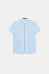 Camisa entallada de color celeste, con cuello mao y manga corta. Presenta un cierre frontal con alamares decorativos.