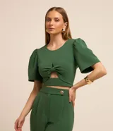 Blusa cropped verde confeccionada en crepé, con cuello redondo, mangas cortas abullonadas y detalle cutout en el delantero.