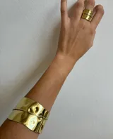 Anillo dorado ancho con textura martillada, hecho artesanalmente en bronce y regulable.