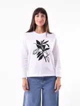 Remera blanca de manga larga con estampado frontal de hojas en color negro.