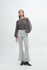 Blusa de terciopelo gris con acabado brillante, cuello redondo y mangas largas abullonadas con puños elásticos.