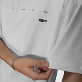 Remera blanca de corte oversize con diseño gráfico estampado en la espalda que incluye texto y un logo central.